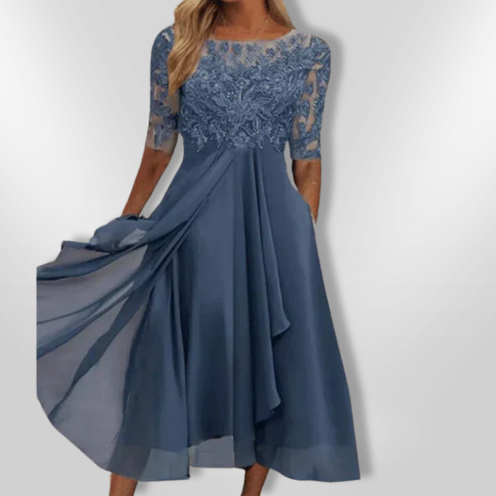 Kvinne iført elegant asymmetrisk festkjole med blonder, perfekt for sommerlige selskaper.