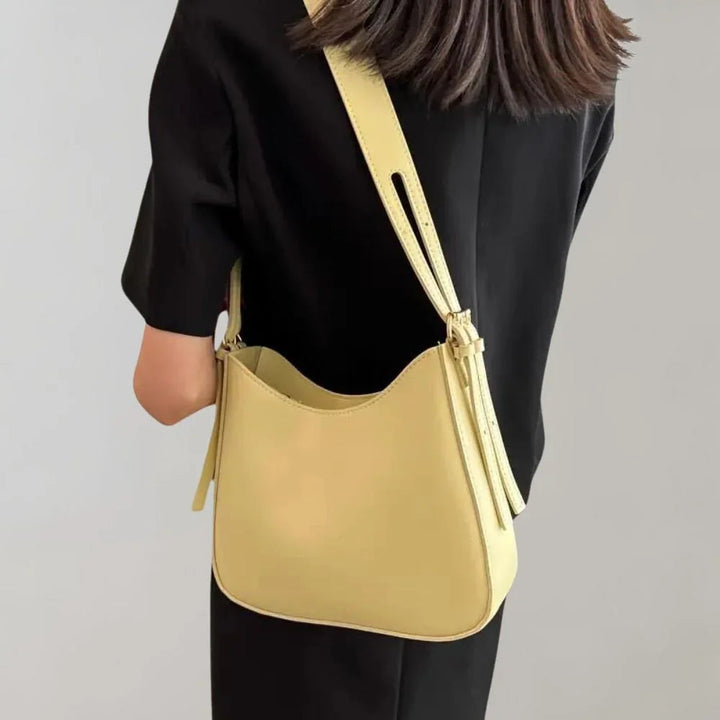 Nærbilde av glidelåslukkingen på en strukturert kvinners crossbody-veske, viser kvalitet og detaljer.