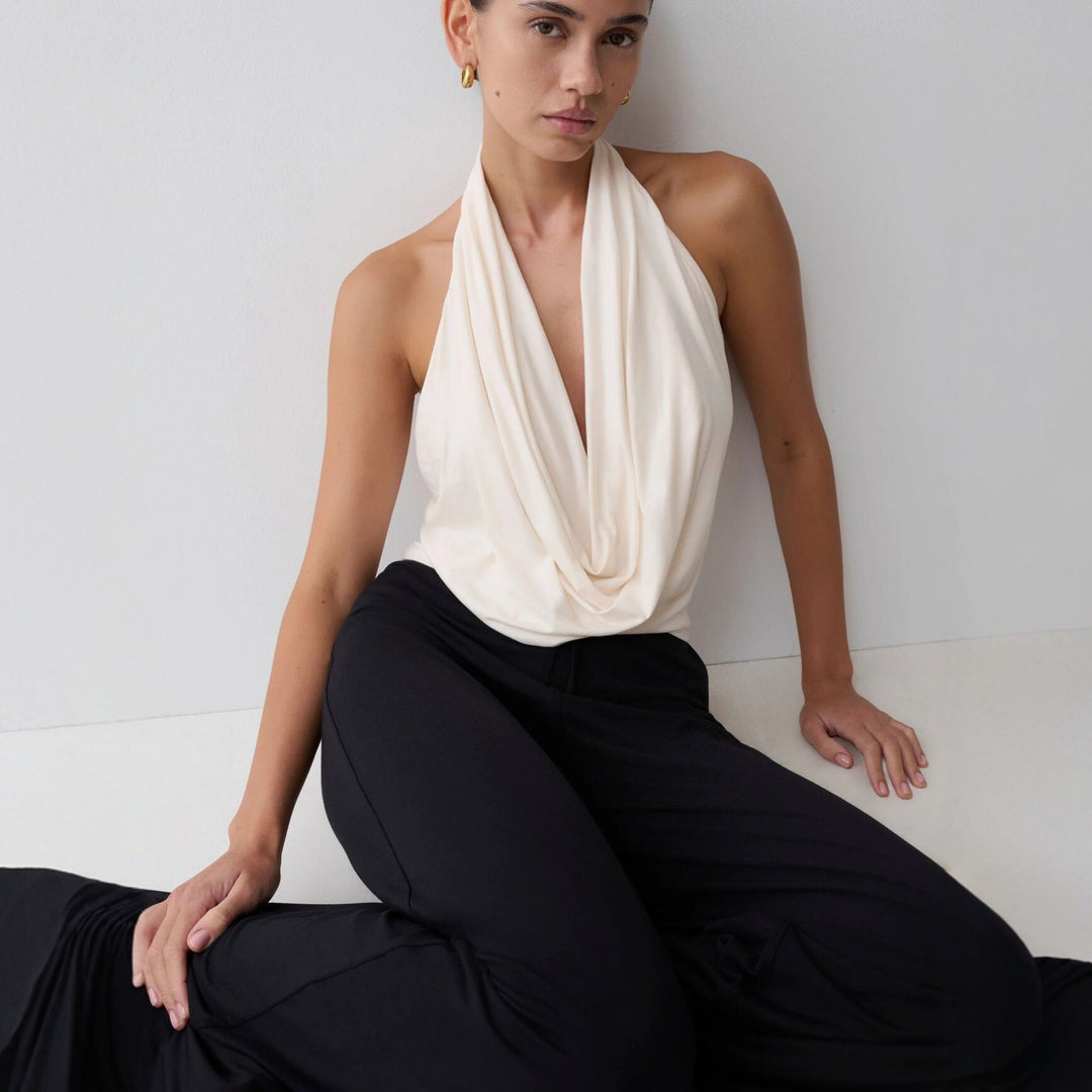 Hvit stilren halterneck-topp med dyp utringning. Elegant dametopp, ideell for sommer og casual chic.