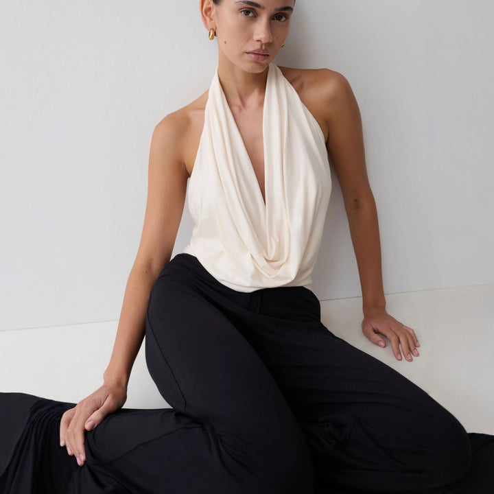 Hvit stilren halterneck-topp med dyp utringning. Elegant dametopp, ideell for sommer og casual chic.