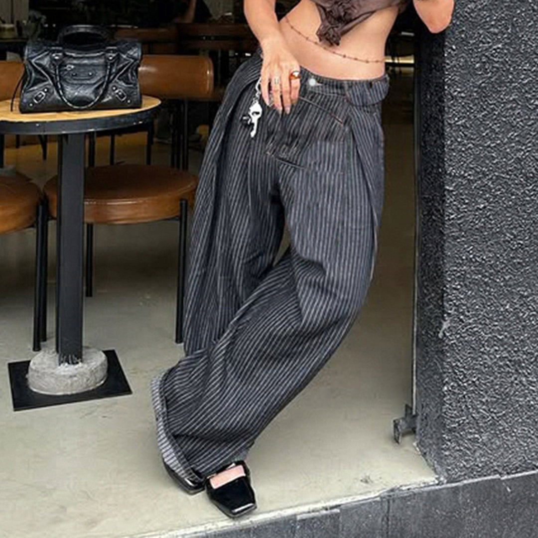 Modell iført svarte vide stripete jeans med høyt liv. Trendy og behagelig for en moderne damegarderobe.