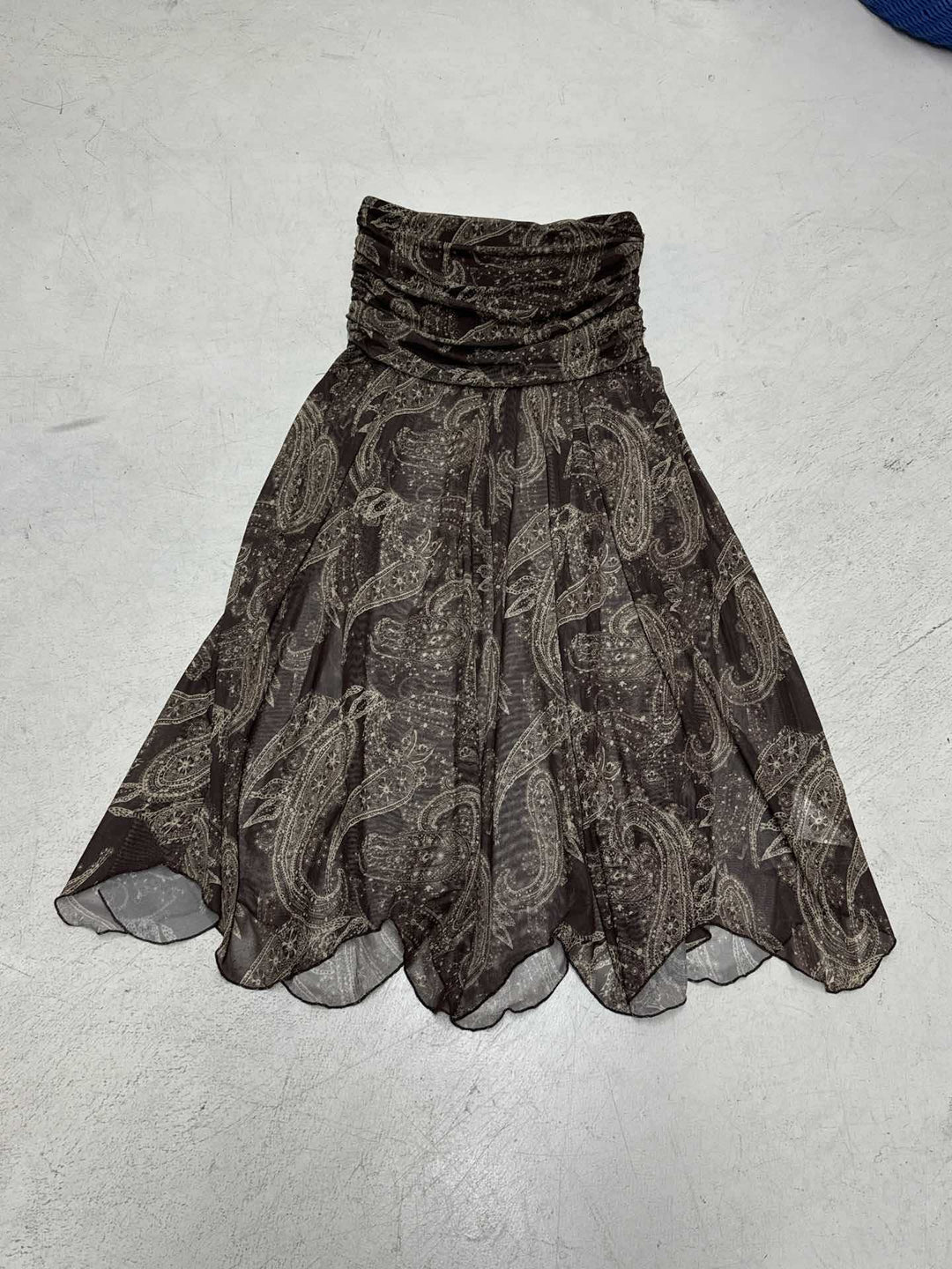Detaljert visning av brunt asymmetrisk kvinneskjørt med paisley-mønster. Mykt stoff, elegant vår/sommerskjørt.