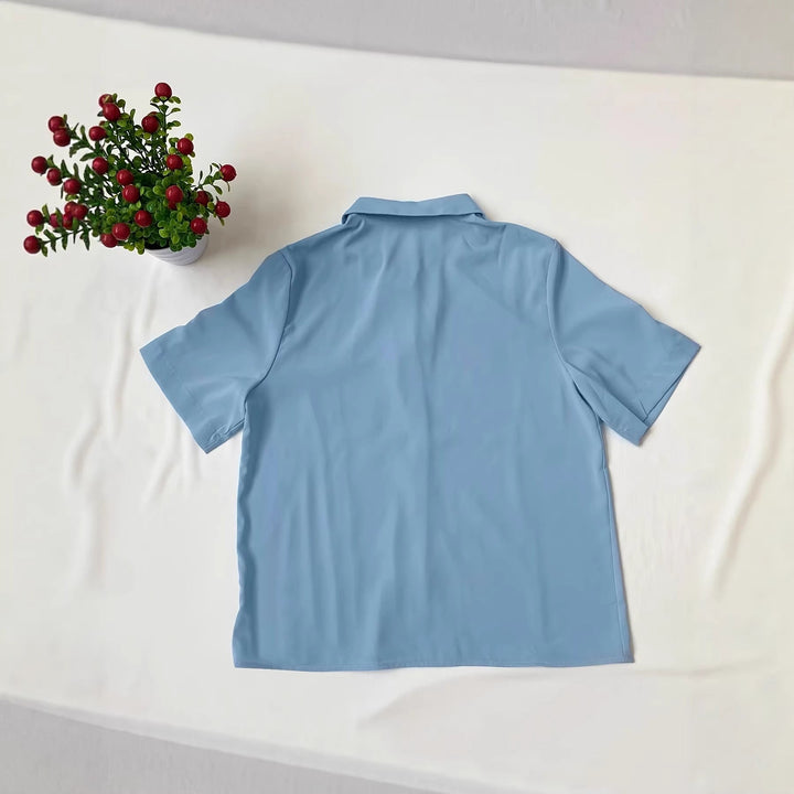 Blå damebluse med korte ermer og brystlomme. Klassisk design som kombinerer mote med optimal komfort.