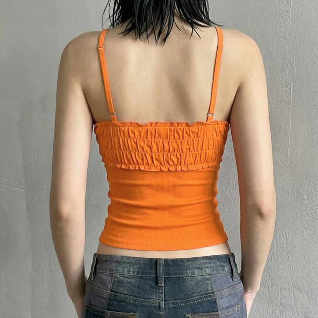 Motebevisst oransje dametopp med stilige volanger og innovative stropper for sommeren.