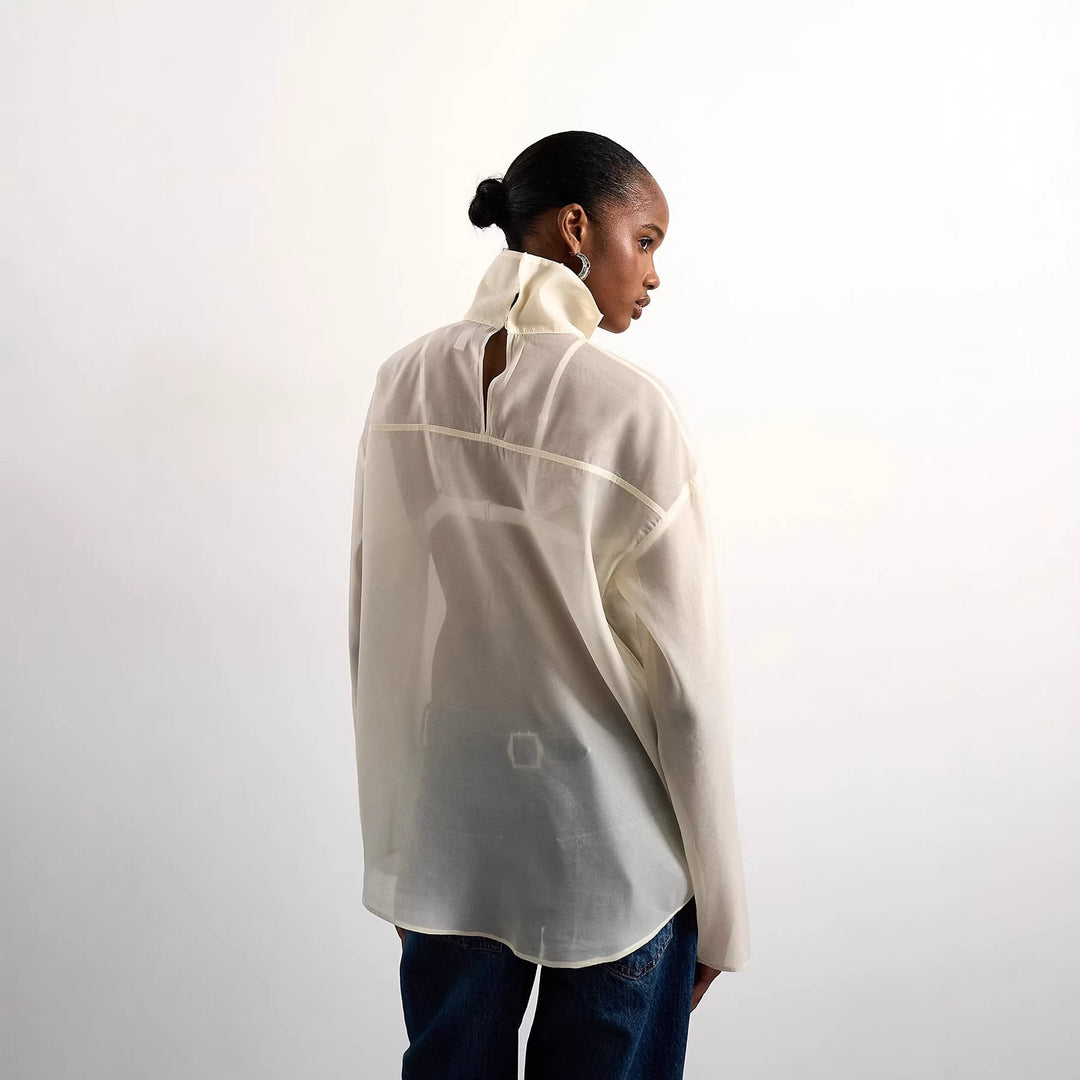 Mote-riktig kremfarget damebluse med høy krage. En elegant og lett sommertopp, perfekt for kvinneklær.