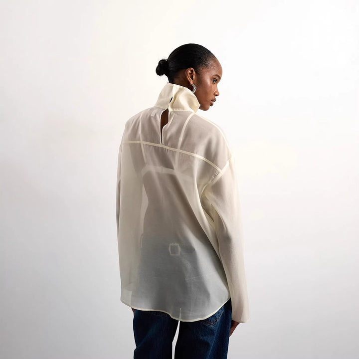 Mote-riktig kremfarget damebluse med høy krage. En elegant og lett sommertopp, perfekt for kvinneklær.