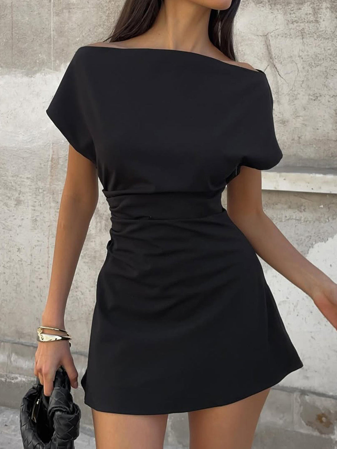 Elegant svart damekjole med asymmetrisk halslinje og flatterende rynker på siden, ideell for fest og spesielle anledninger.