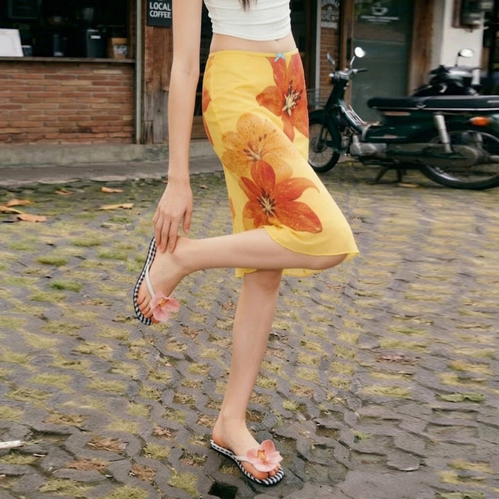 Komfortabelt gult dameskjørt med fargerikt blomsterprint og elastisk midje, elegant midi-lengde.