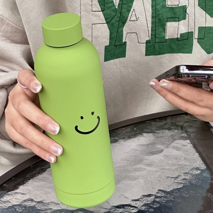 Miljøvennlig isolert drikkeflaske for dame, ideell som reiseflaske eller treningsutstyr med smiley-motiv.