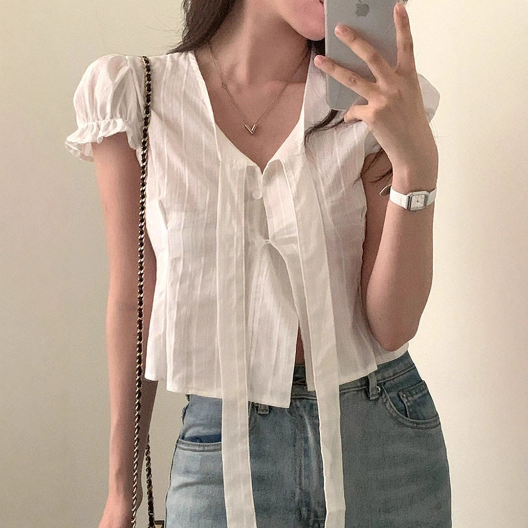 Elegant hvit sommerbluse for kvinner, med stilige volangermer, V-hals og dekorative knytesnorer.