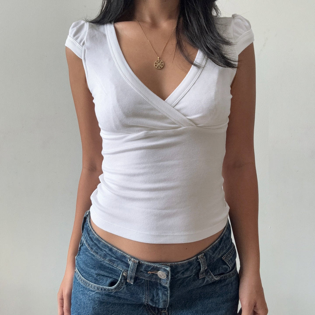 Klassisk hvit bluse med elegant v-hals, figurnær fasong, perfekt for en sofistikert vår- eller sommerlook.