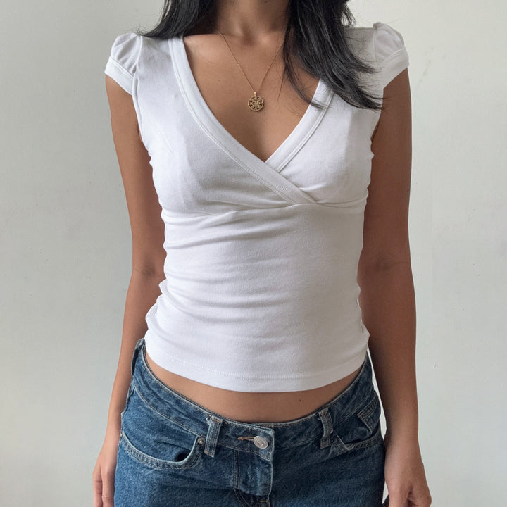 Klassisk hvit bluse med elegant v-hals, figurnær fasong, perfekt for en sofistikert vår- eller sommerlook.