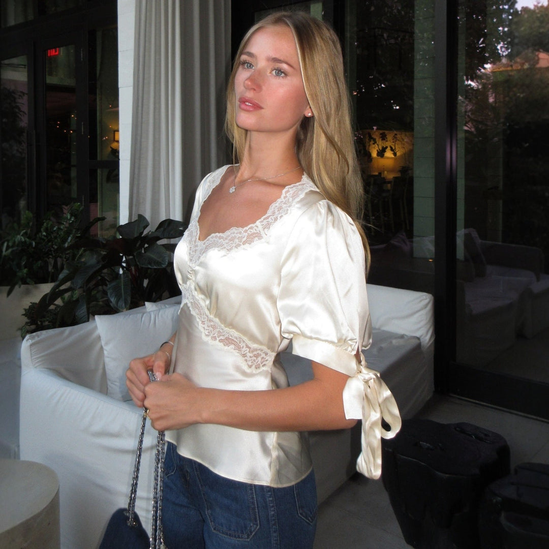 Elfenbensfarget damesatinbluse. Elegant langermet blondebluse; feminin stil, kontor eller fest.