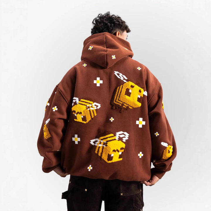 Stilig lys brun damegenser med hette og trendy biemotiv. Ideell for en komfortabel, casual stil.