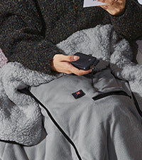 Kvinne slapper av med et varmt oppvarmet kosepledd i fleece. Perfekt for vintervarme, innekos og komfortabel avkobling.