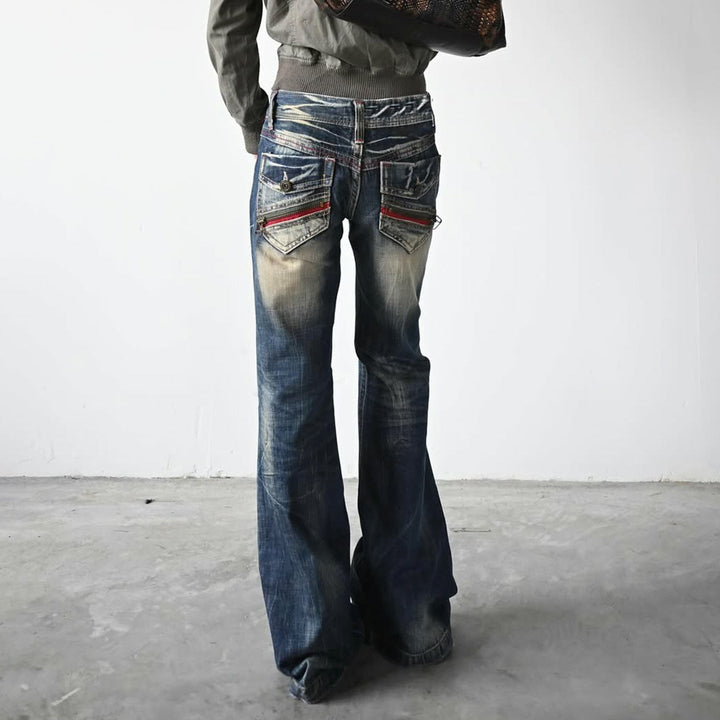 Nærbilde av detaljer på blå flared damejeans, som viser det unike bruktutseendet og slitte partier.