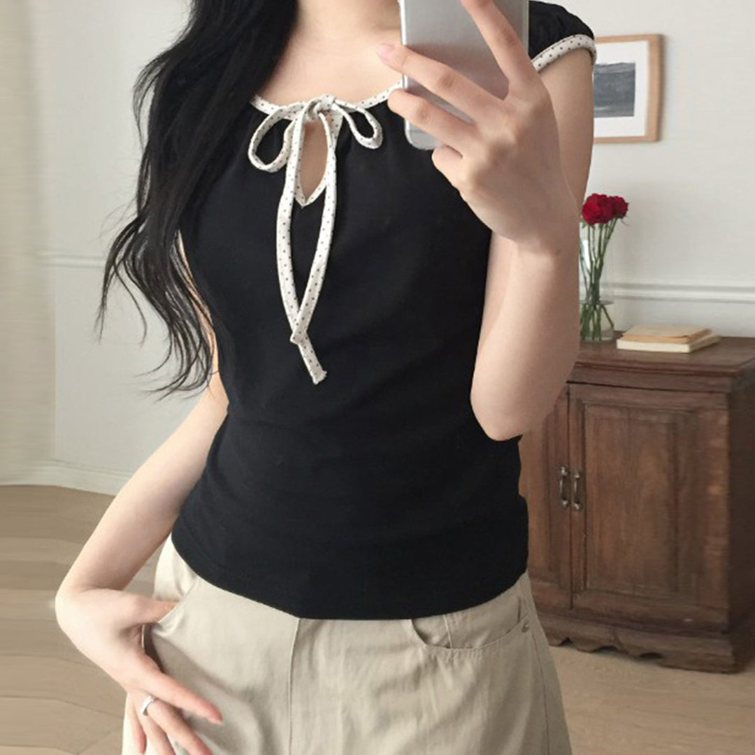 Svart damebluse med lekne puffermer og elegant sløyfebinding foran, perfekt for vår og sommer.