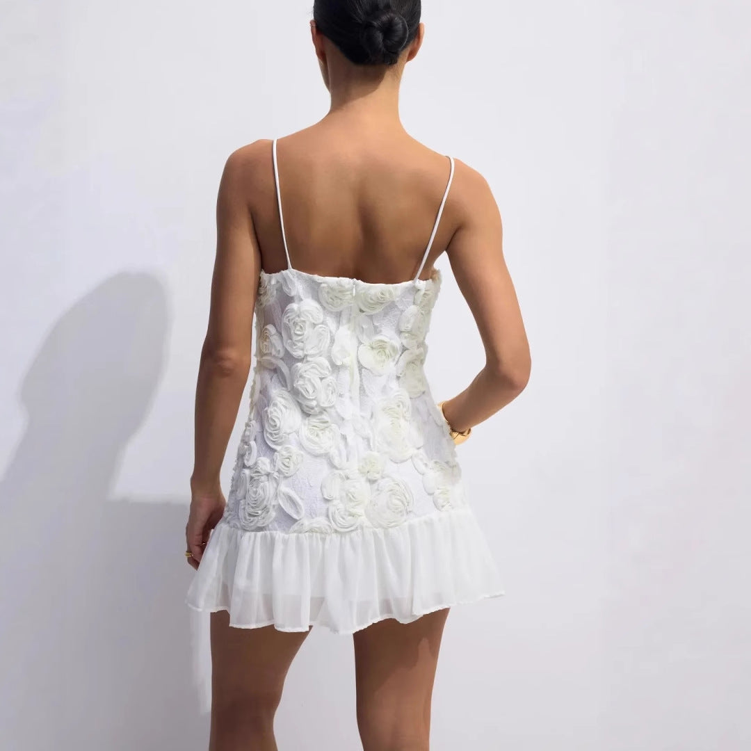 Modell iført elegant hvit damekjole med blomster og ruffles, en stilig sommerkjole perfekt for fest.