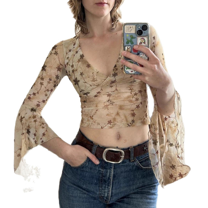 Modell bærer en elegant langermet spissbluse med volanger, viser frem moderne og feminin stil.