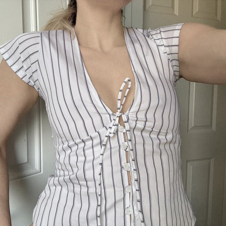 Dame kortermet topp med volangdetaljer og elegant ryggsnitt, perfekt for sommer og vår. Trendy og stilfull.