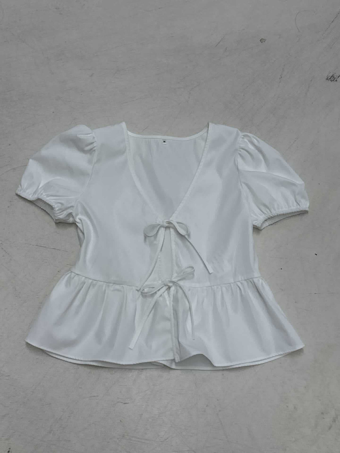 Trendy innpakningsbluse for dame med voluminøse puffermer og flatterende peplumkant. En chic stilfull topp.