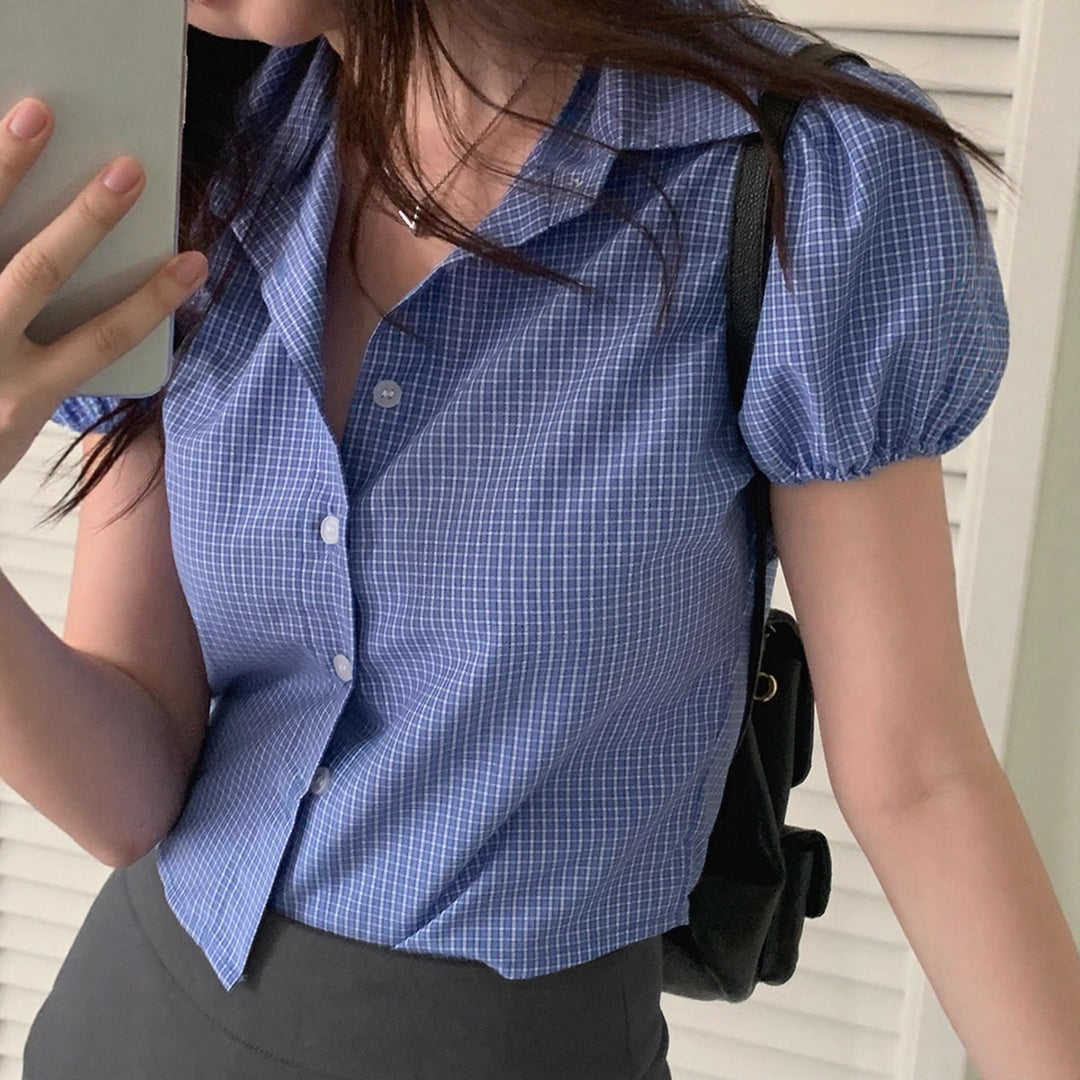 Blå kortermet damebluse med delikat rutemønster og feminine puffermer. Tidløs vår- og sommerlook.