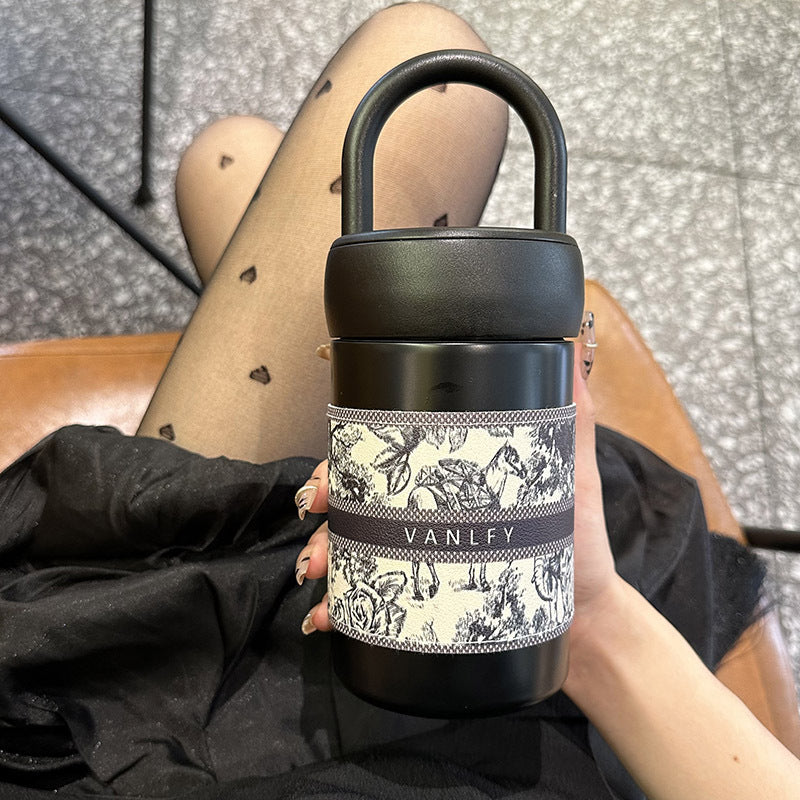 Reisevennlig termokopp med stilfullt design og håndtak for dame. Ideell for te, kaffe og vann.
