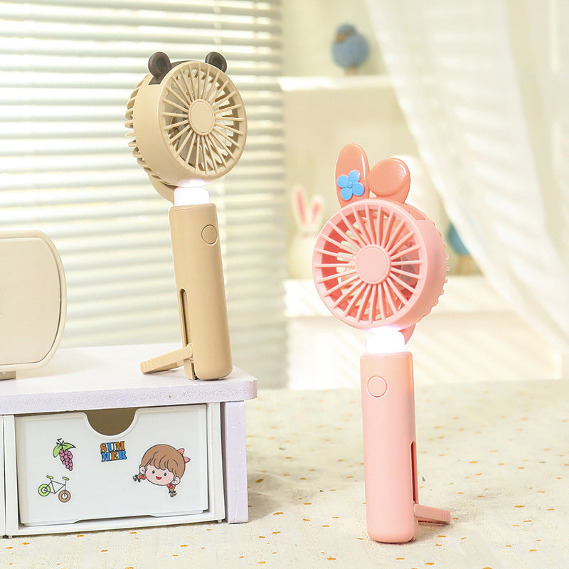Rosa bærbar håndvifte for kvinner med LED og dyreører. USB-ladbar sommergadget for reise.
