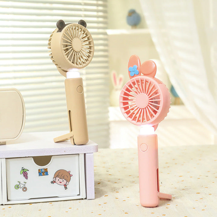 Rosa bærbar håndvifte for kvinner med LED og dyreører. USB-ladbar sommergadget for reise.