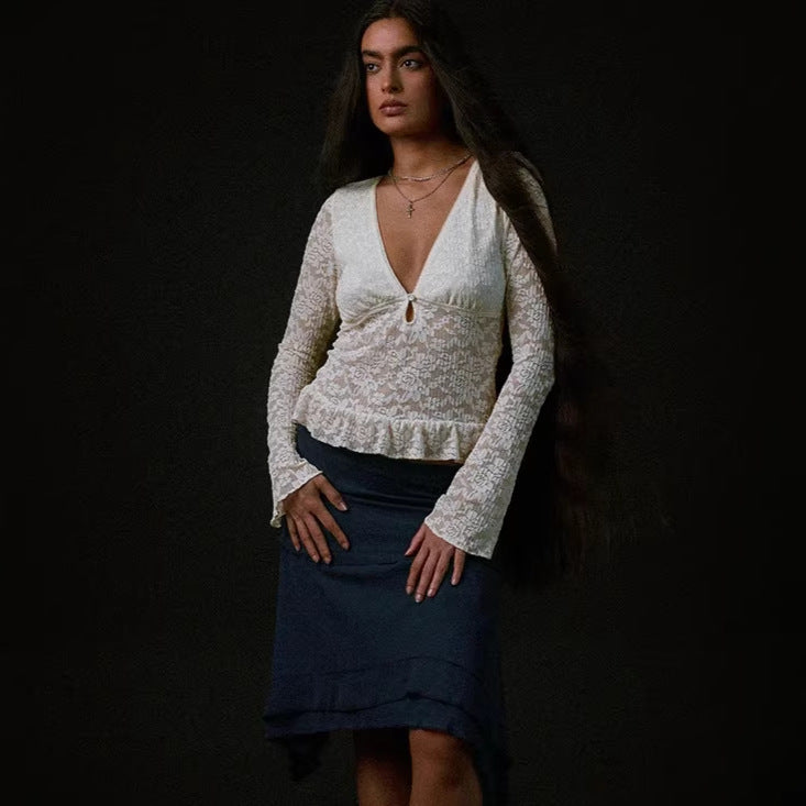 Elegant hvit damebluse med dyp V-hals og volanger på ermer og kant, perfekt for sommer og fest.