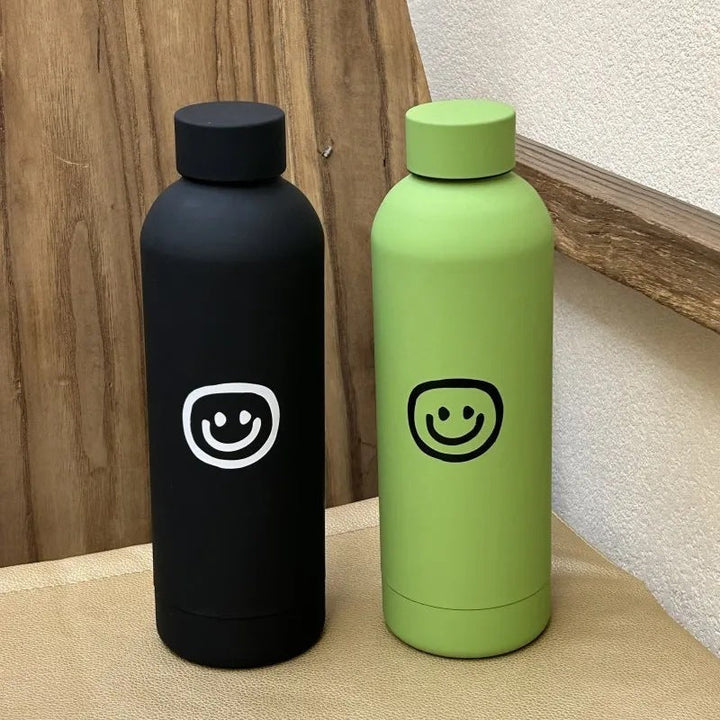 Nærbilde av 500ml termosflaske med lekent gult smiley-ansikt. Rustfritt stål, perfekt gave.