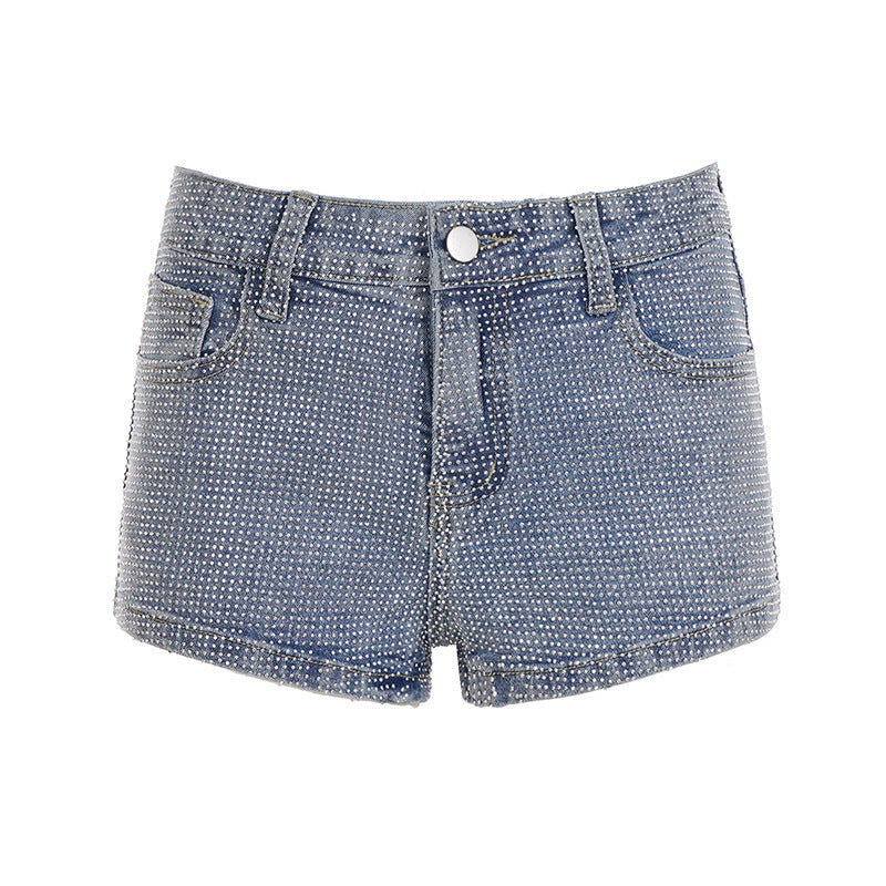 Detalj av den glitrende utsmykningen på kanten av blå denimshorts, trendy høy midje sommershorts for dame.
