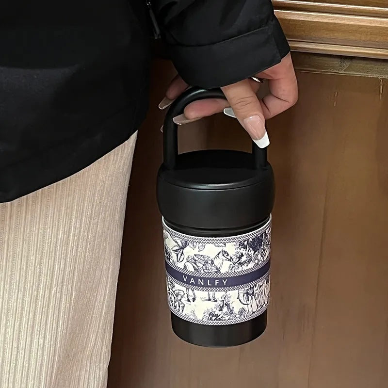 Isolerende drikkeflaske/kopp for dame med solid håndtak. Allsidig termokopp for kontor og utflukter.