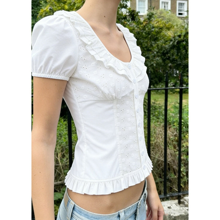 Stilren hvit damebluse med blomsterprint, volanger og puffermer for en chic stil.