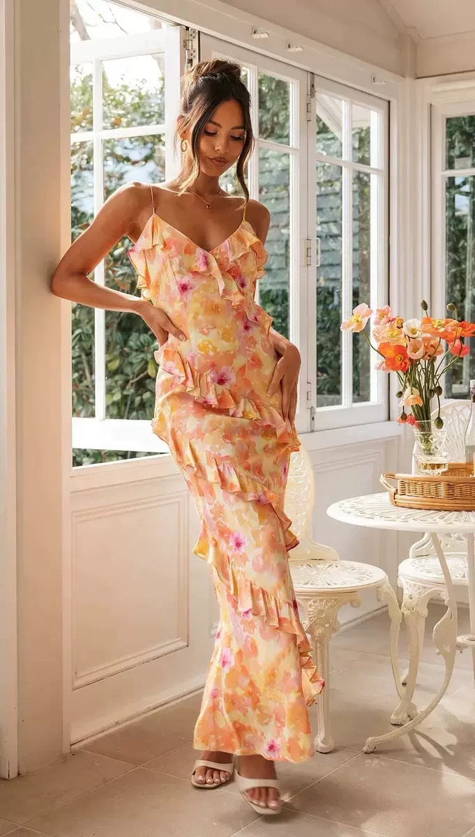 Kvinne bærer vakker, lang blomsterkjole med volanger. En elegant og fargerik maxikjole for vår og sommer.