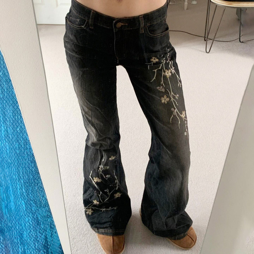 Mørke damejeans med utvidede ben og detaljert brodert blomsterdesign. Ideell for vår- og sommerkolleksjonen.