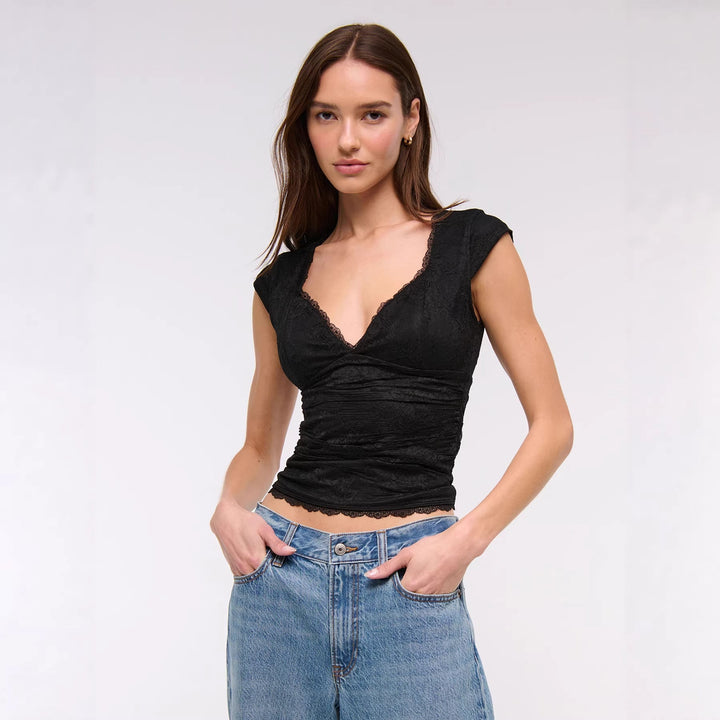 Svart langermet kvinnebluse med V-hals og elegante volanger på ermene, perfekt for vår og sommer.
