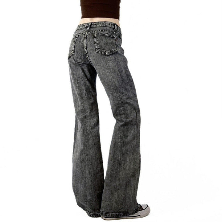 Modell viser trendy passform av grå flared jeans for kvinner, med stilig blomsterbroderi for en casual look.