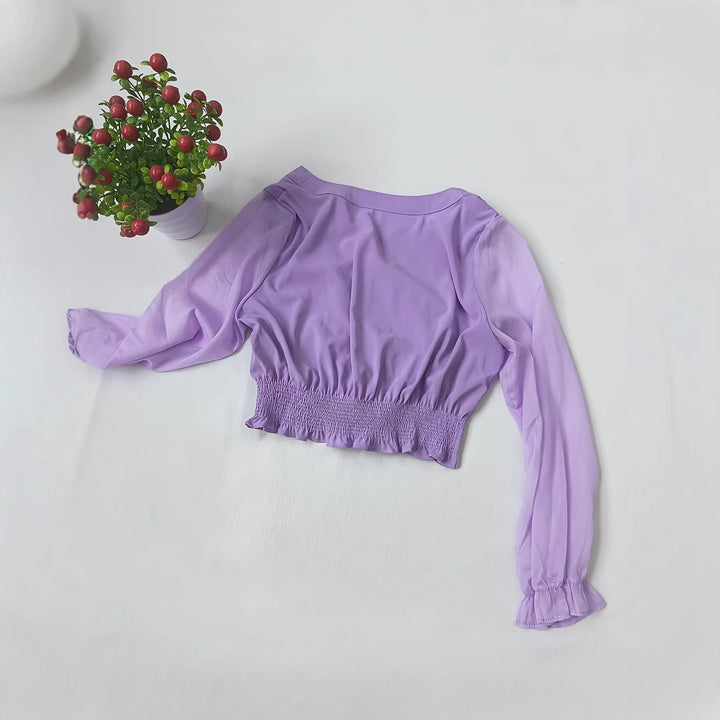 Detaljert bilde av lilla damebluse med volanger på ermer og hals, viser stoff og tekstur.