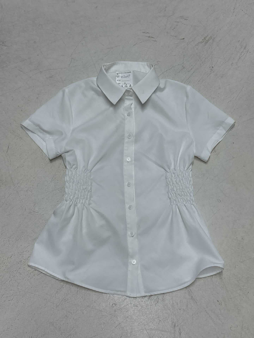 Kortermet damebluse med feminine rynker og knappedetaljer. Perfekt som kontor-, sommer- eller festtopp.