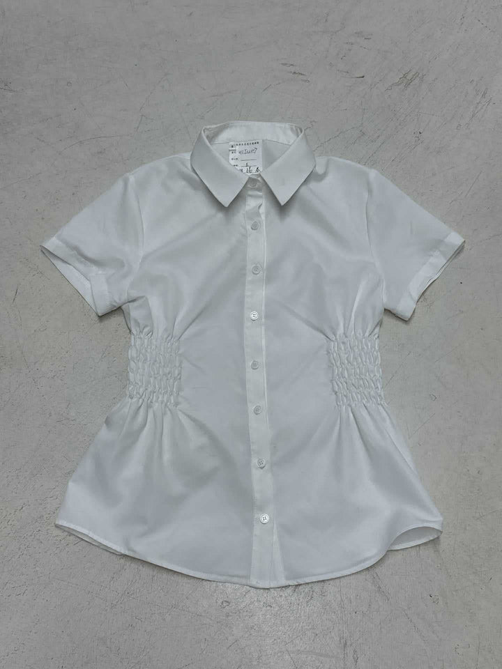 Kortermet damebluse med feminine rynker og knappedetaljer. Perfekt som kontor-, sommer- eller festtopp.