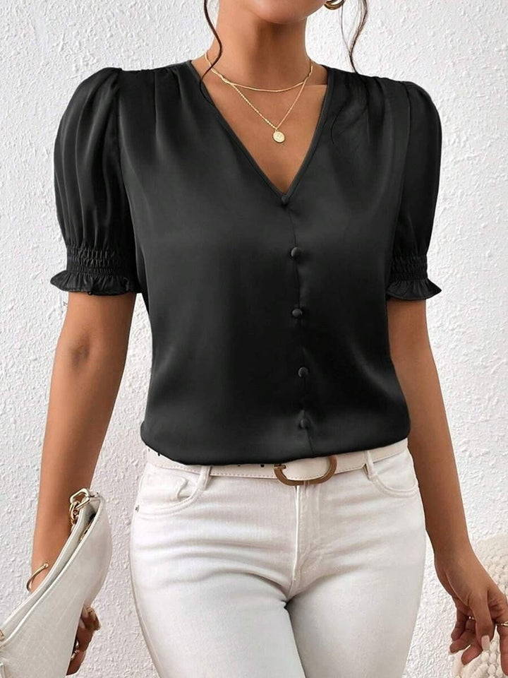 Allsidig damebluse med elegante puffermer og knapper, lett å style for ulike anledninger.