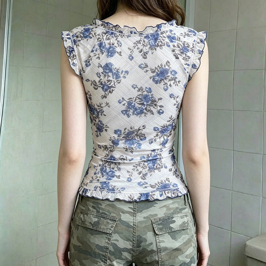 Nærbilde av elegant damebluse: blomstermønster, volanger og V-hals som fremhever feminin passform.