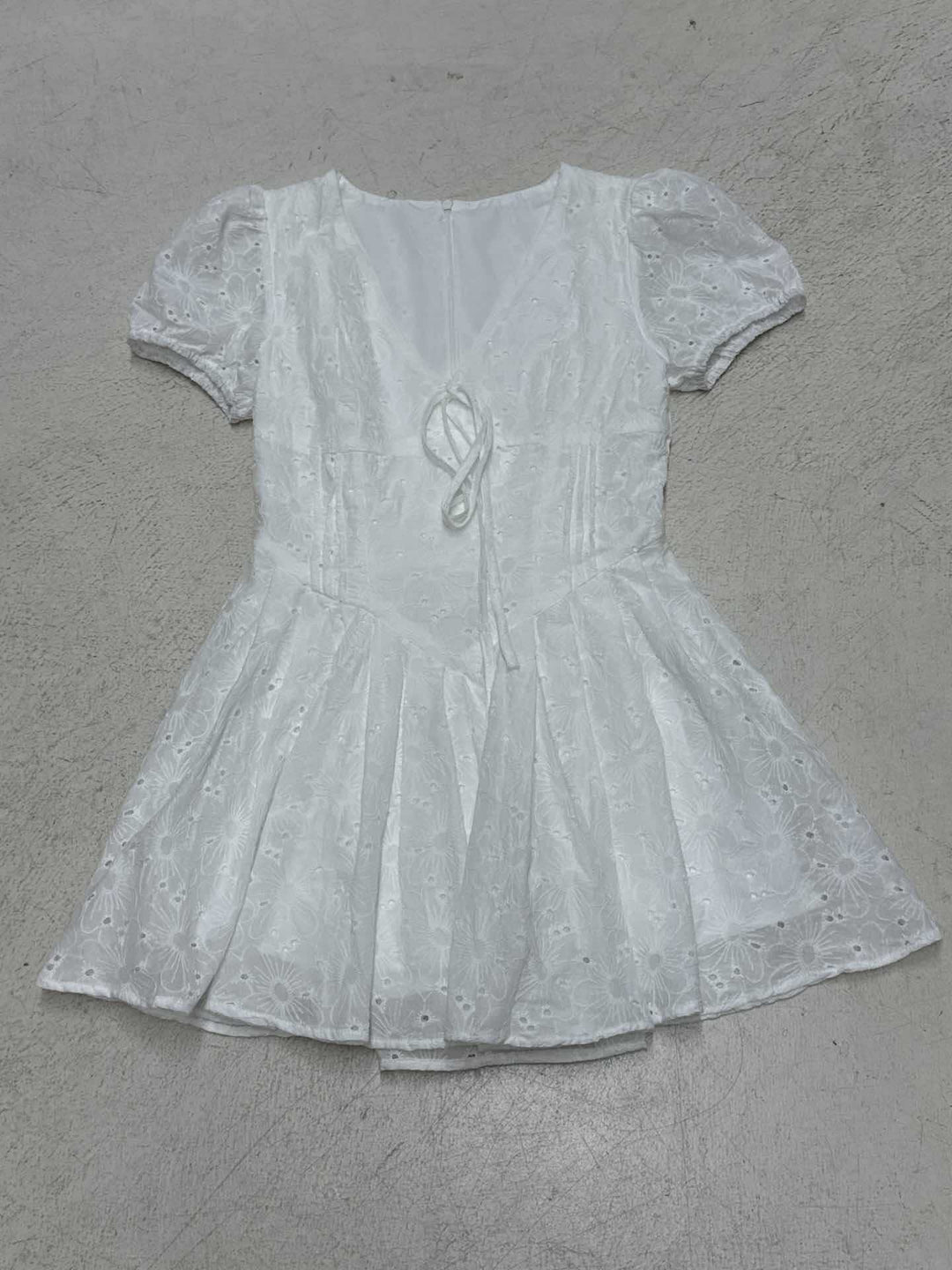 Elegant V-hals sommerkjole i hvit med rysjer, korte ermer og et feminint snitt. Perfekt til enhver anledning.