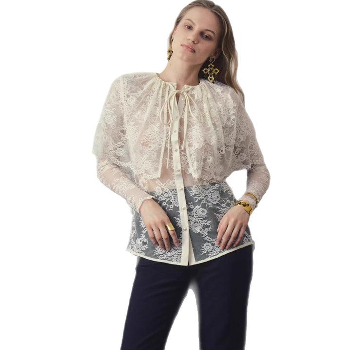Hvit festbluse med moderne design, sløyfe i halsen og transparente ermer for en chic look.