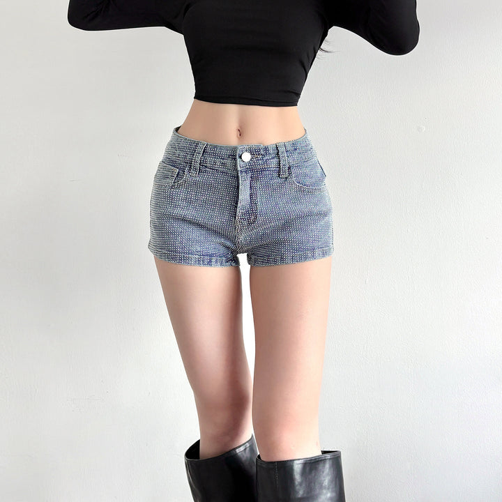 Nærbilde av skinnende rhinestones på blå denimshorts med høy midje, glamorøs festivalstil.