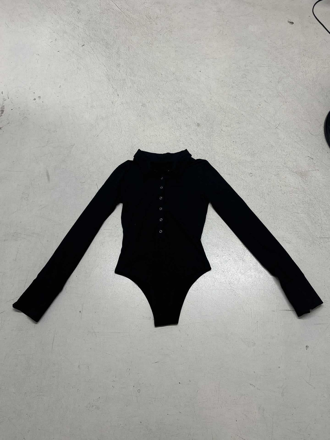 Nærbilde av den elegante knappestolpen på en figurnær langermet damebodysuit.