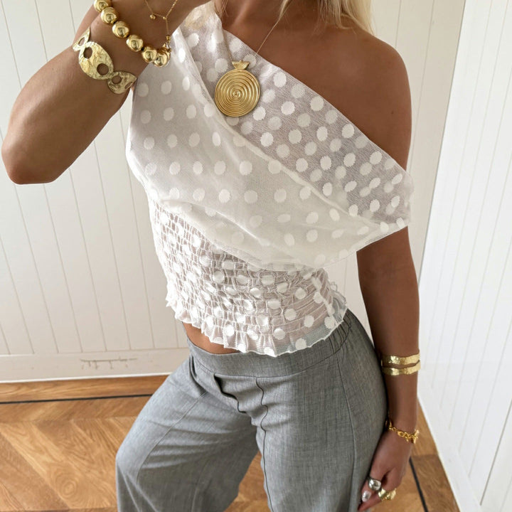 Mote-bluse med unikt asymmetrisk snitt og delikate volanger, en moderne og behagelig topp for kvinner.