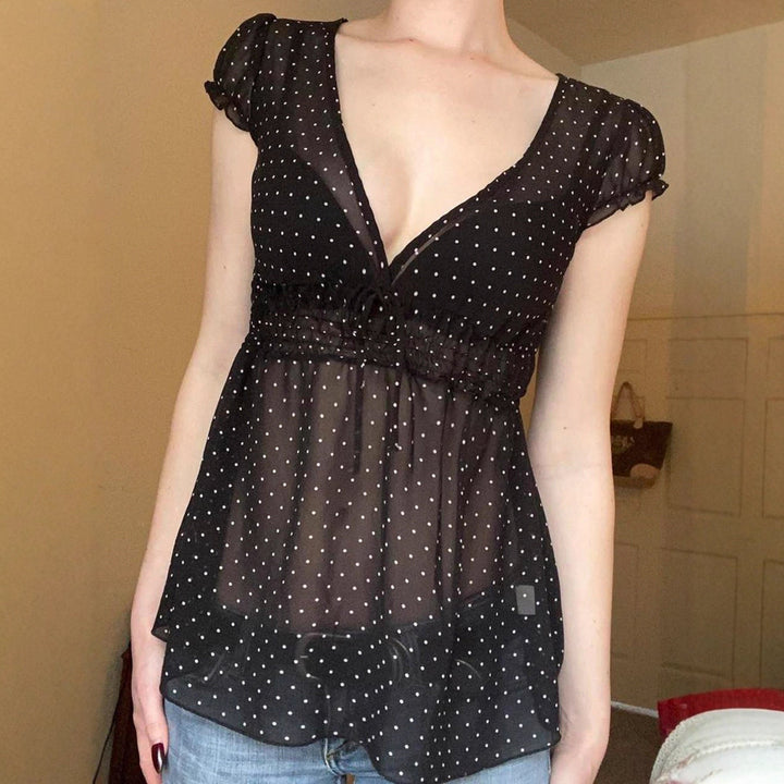 Modell i elegant svart polkaprikket volangbluse, viser flatterende passform og feminin stil.