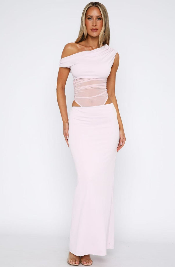 Maxikjole i rosa med elegant asymmetrisk hem og delikate transparente ermer, flott festkjole for kvinner.